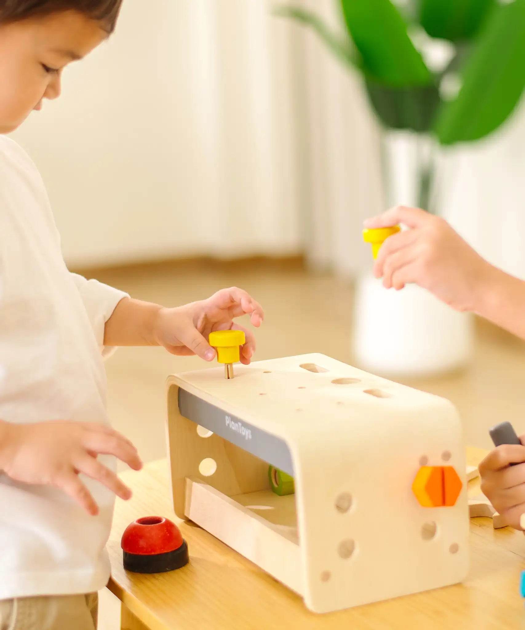 Children playing with the PlanToys little tool bench set.