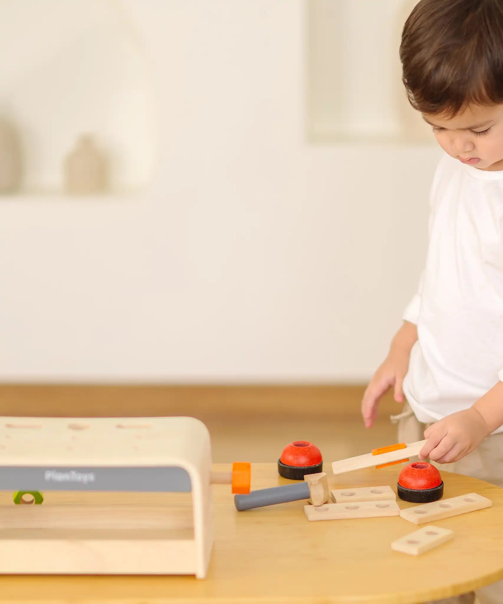 Child playing with the PlanToys little tool bench set.