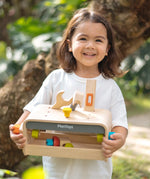 Child holding the PlanToys little tool bench set. 