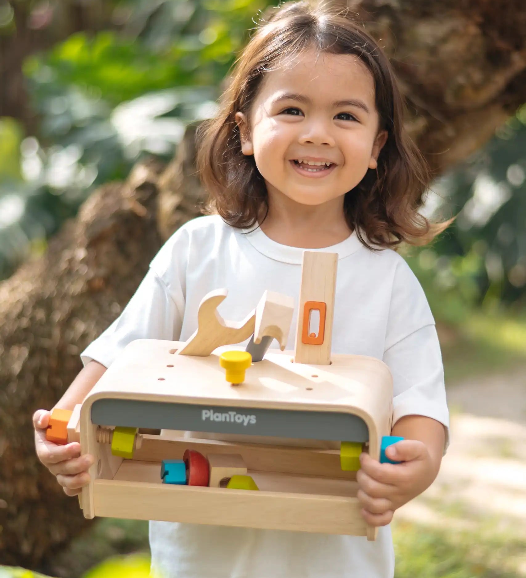 Child holding the PlanToys little tool bench set. 