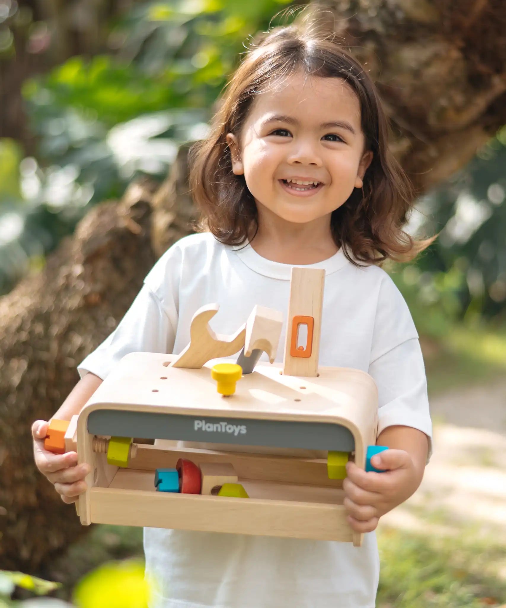Child holding the PlanToys little tool bench set. 