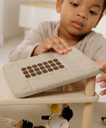 A close up of a child playing the with Plantoys wooden living room showing the sunlight roof being put on the support pillars