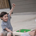 A child playing with the PlanToys Magnetic Board Game, he has his fist in the air with a smile on his face. 
