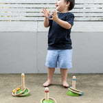 A child clapping their hand with delight whilst playing with the PlanToys Meadow Ring Toss game. 
