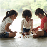 Three children sitting on the floor playing with the PlanToys Mini Memo Game set. 