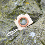A PlanToys Camera placed on a rock outdoors. 