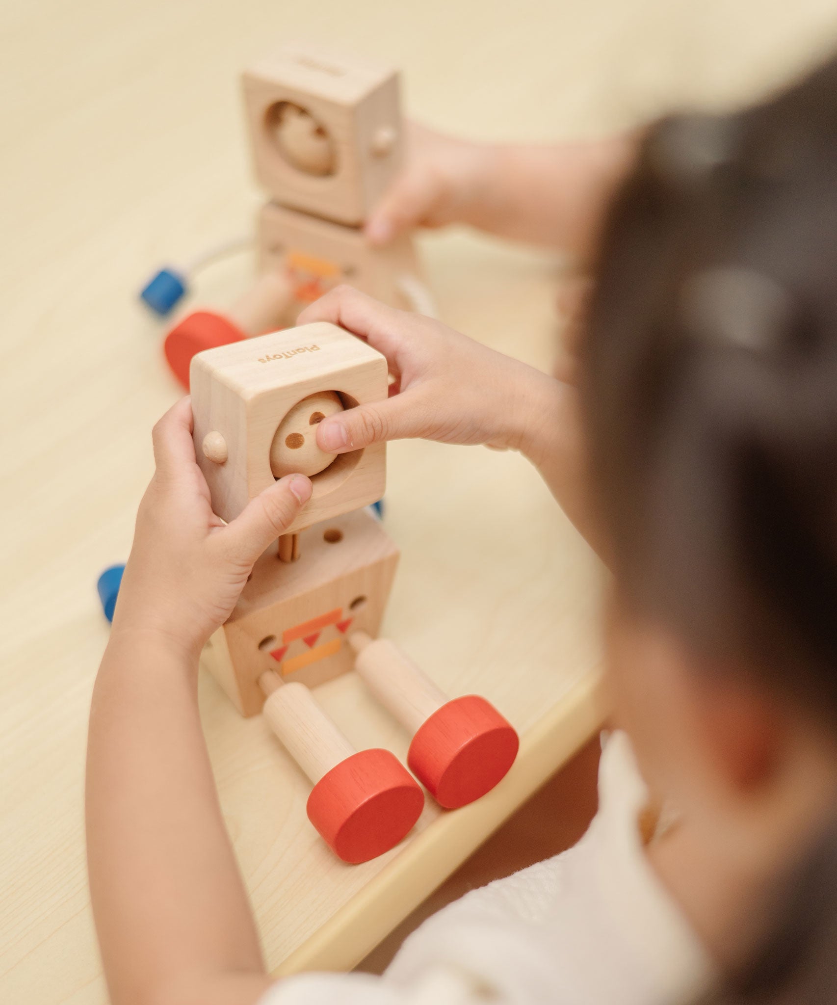 A child playing with the PlanToys Mood Bot Emotions Wooden Toy Robot. PlanToys range of toys are made from sustainably sourced rubberwood, we're proud stockists of PlanToys here at Babipur. 