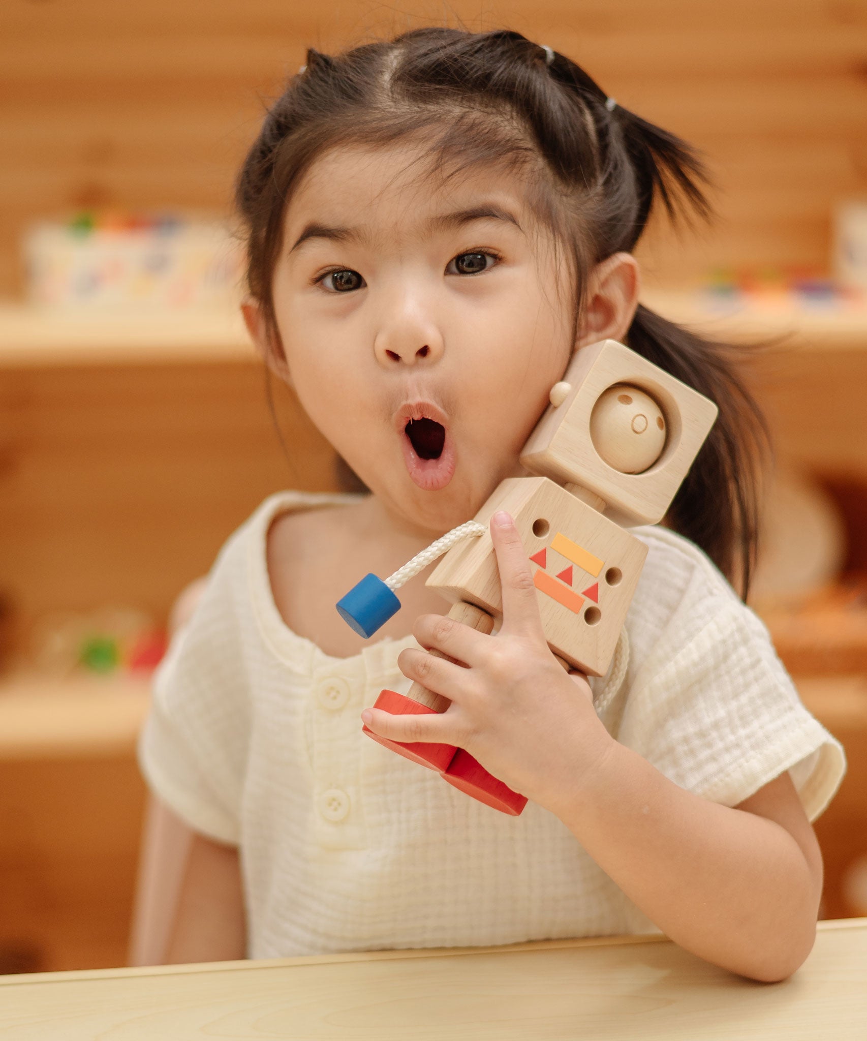 A child holding onto the PlanToys Mood Bot Emotions Wooden Toy Robot. PlanToys range of toys are made from sustainably sourced rubberwood, we're proud stockists of PlanToys here at Babipur. 