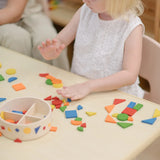 Child playing with the PlanToys mosaic wooden pattern making set taking the brightly coloured pieces out of the wooden storage tub.