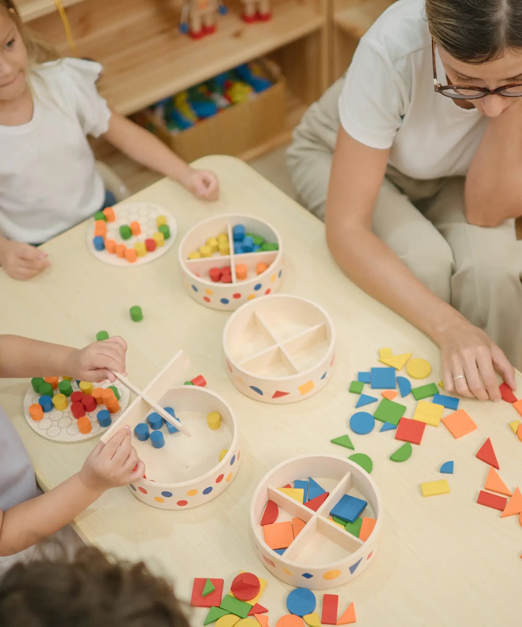 Children playing with the PlanToys mosaic wooden pattern making sets taking the brightly coloured pieces out of the wooden storage tub.