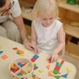 Child creating a colourful pattern using the wooden pieces from the PlanToys Mosaic wooden pattern making toy.
