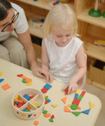 Child creating a colourful pattern using the wooden pieces from the PlanToys Mosaic wooden pattern making toy.