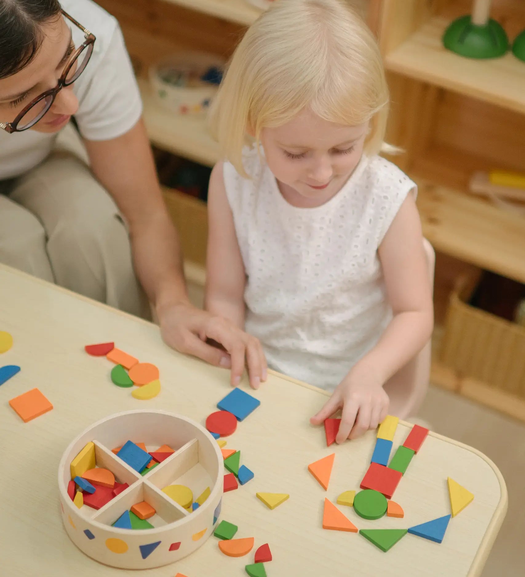 Child creating a colourful pattern using the wooden pieces from the PlanToys Mosaic wooden pattern making toy.