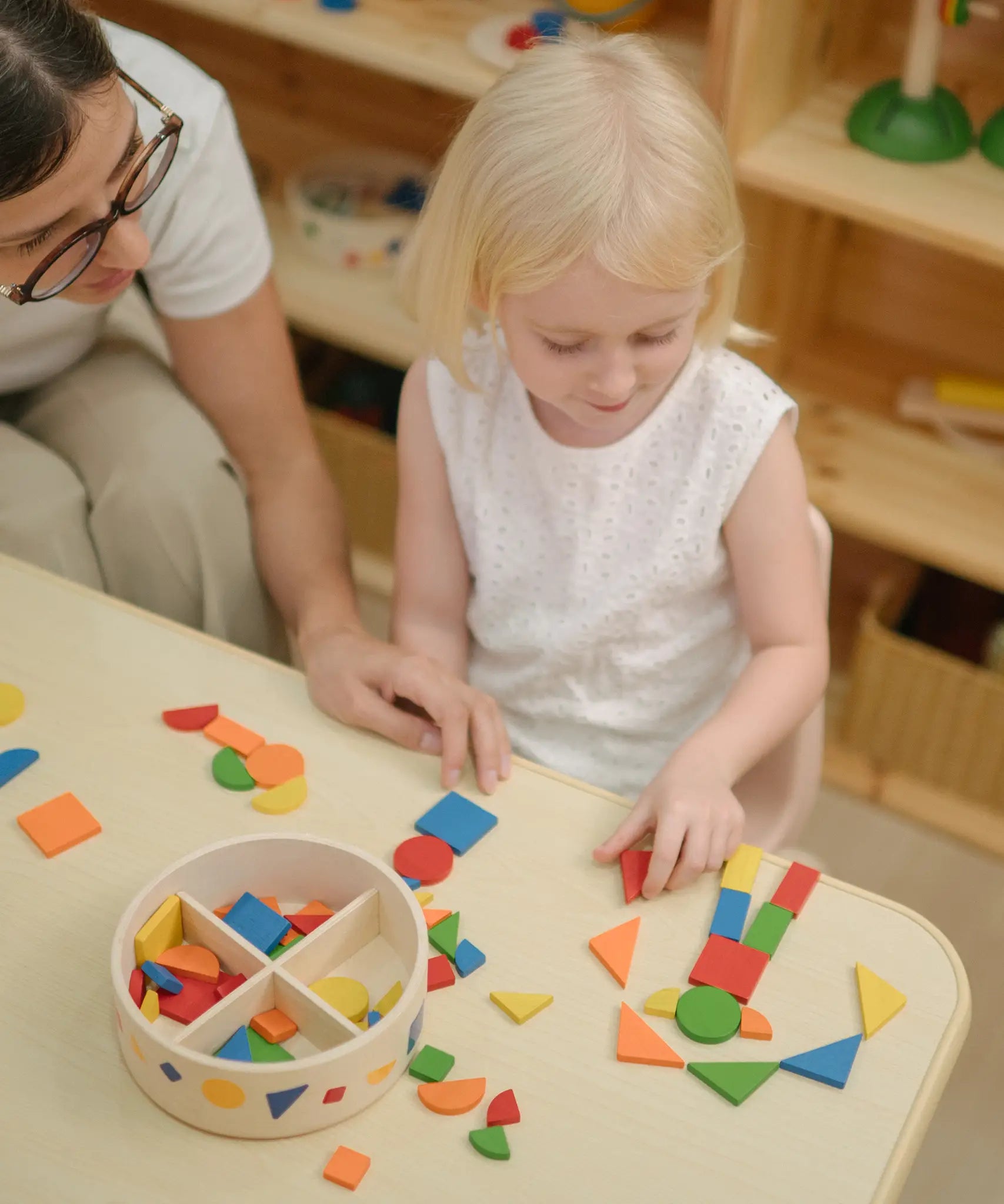 Child creating a colourful pattern using the wooden pieces from the PlanToys Mosaic wooden pattern making toy.