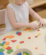 Child creating a colourful patterns using the wooden pieces from the PlanToys Mosaic wooden pattern making toy.