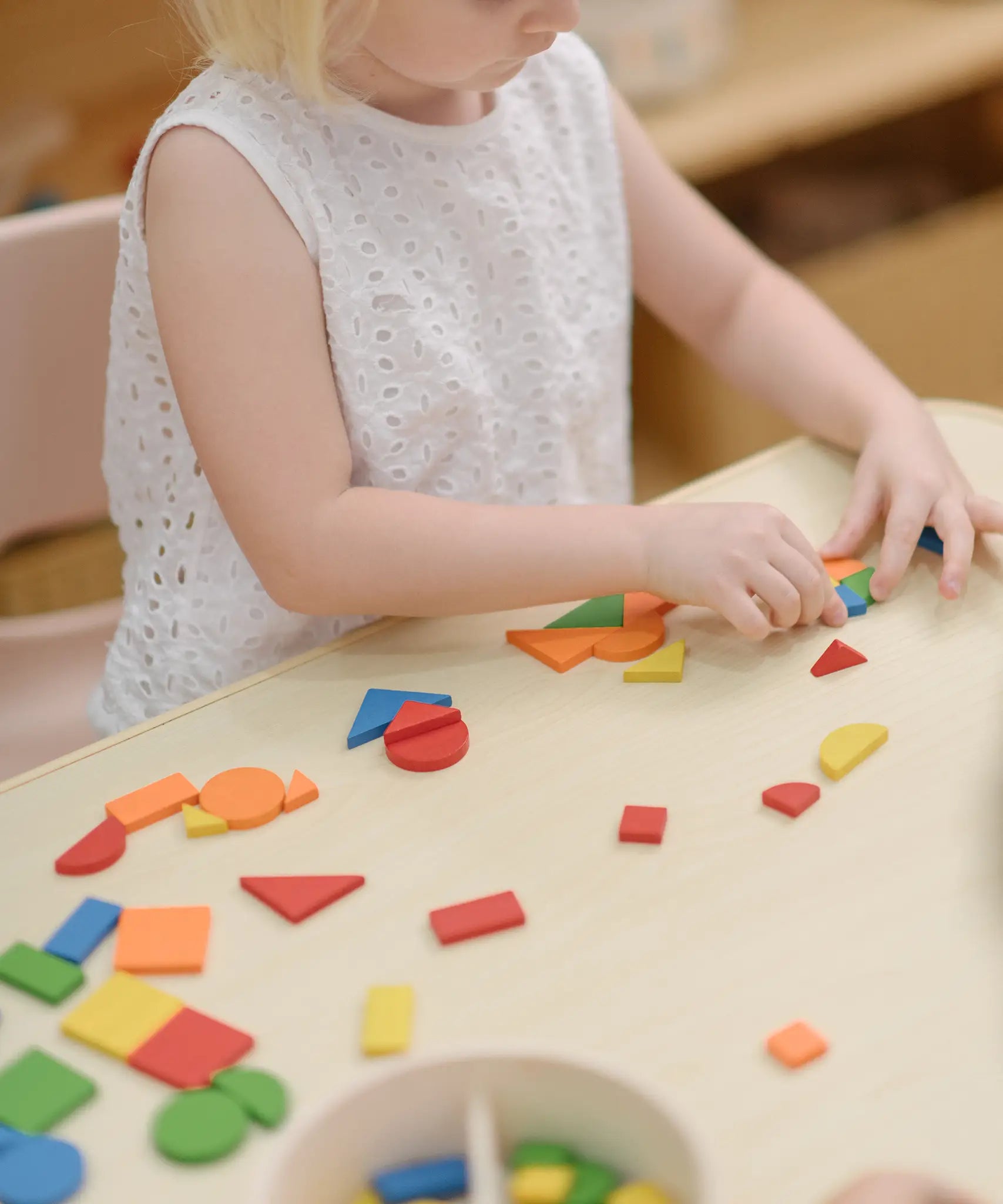 Child creating a colourful patterns using the wooden pieces from the PlanToys Mosaic wooden pattern making toy.