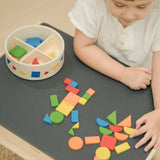Child creating a colourful pattern using the wooden pieces from the PlanToys Mosaic wooden pattern making toy.