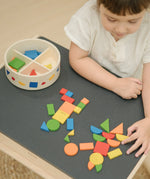 Child creating a colourful pattern using the wooden pieces from the PlanToys Mosaic wooden pattern making toy.