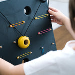 Close up of a child playing with the PlanToys wooden wall ball board game