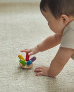 Close up of young child spinning the PlanToys flexi jellyfish toy around on a beige carpet