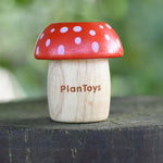 A red PlanToys Mushroom Kaleidoscope on a round fence post outdoors. 