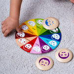 A close up of a child's hand playing with the PlanToys My Mood Memo game. 