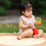 Child playing with the PlanToys Nesting Cylinders 3 piece wooden toy. Red, yellow and blue coloured wooden cylinder shaped wooden pieces that nest inside each other. 
