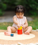 Child playing with the PlanToys Nesting Cylinders 3 piece wooden toy. Red, yellow and blue coloured wooden cylinder shaped wooden pieces that nest inside each other. 