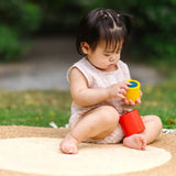 Child playing with the PlanToys Nesting Cylinders 3 piece wooden toy. Red, yellow and blue coloured wooden cylinder shaped wooden pieces that nest inside each other. 