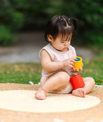 Child playing with the PlanToys Nesting Cylinders 3 piece wooden toy. Red, yellow and blue coloured wooden cylinder shaped wooden pieces that nest inside each other. 