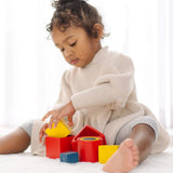 Child playing with PlanToys nesting boxes, triangles and cylinders.