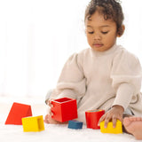 Child playing with PlanToys nesting boxes, triangles and cylinders.