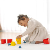 Child playing with PlanToysnesting boxes, triangles and cylinders.