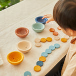 Close up of child playing with the PlanToys plastic-free Waldorf cups and counters set on a table