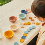 Close up of child playing with the PlanToys plastic-free Waldorf cups and counters set on a table