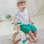 A child sitting on the side of the PlanToys Palomino Rocking Horse. 