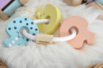 A PlanToys Pastel Baby Key Rattle toy placed on a sheepskin rug. 