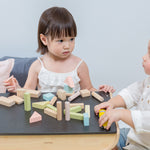 Two children sitting at the PlanToys desk playing with the PlanToys Pastel Blocks set. 
