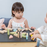 Two children sitting at the PlanToys desk playing with the PlanToys Pastel Blocks set. 