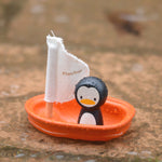 The PlanToys Penguin Sailing Boat placed on wet stone surface. 