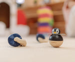 A PlanToys Penguin Wobbler wooden baby toy placed next to other wooden toys. A circular shaped penguin toy that wobbles when placed on a flat surface. PlanToys range of toys are made from sustainably sourced rubberwood, we're proud stockists of PlanToys here at Babipur. 