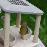 A close up of the green coloured Nin peg doll placed on the toilet from the PlanToys PlanSpace bathroom set.