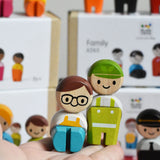 Two dolls from the PlanToys PlanWorld wooden doll service crew in an adult's hand.