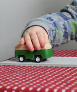 A close up of the green camper from the PlanToys Planworld Cars set being pushed along by a child's hand. 