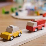 Yellow taxi and red fire engine from the  PlanToys PlanWorld vehicle wooden toy vehicles set placed on a wooden PlanToys road.