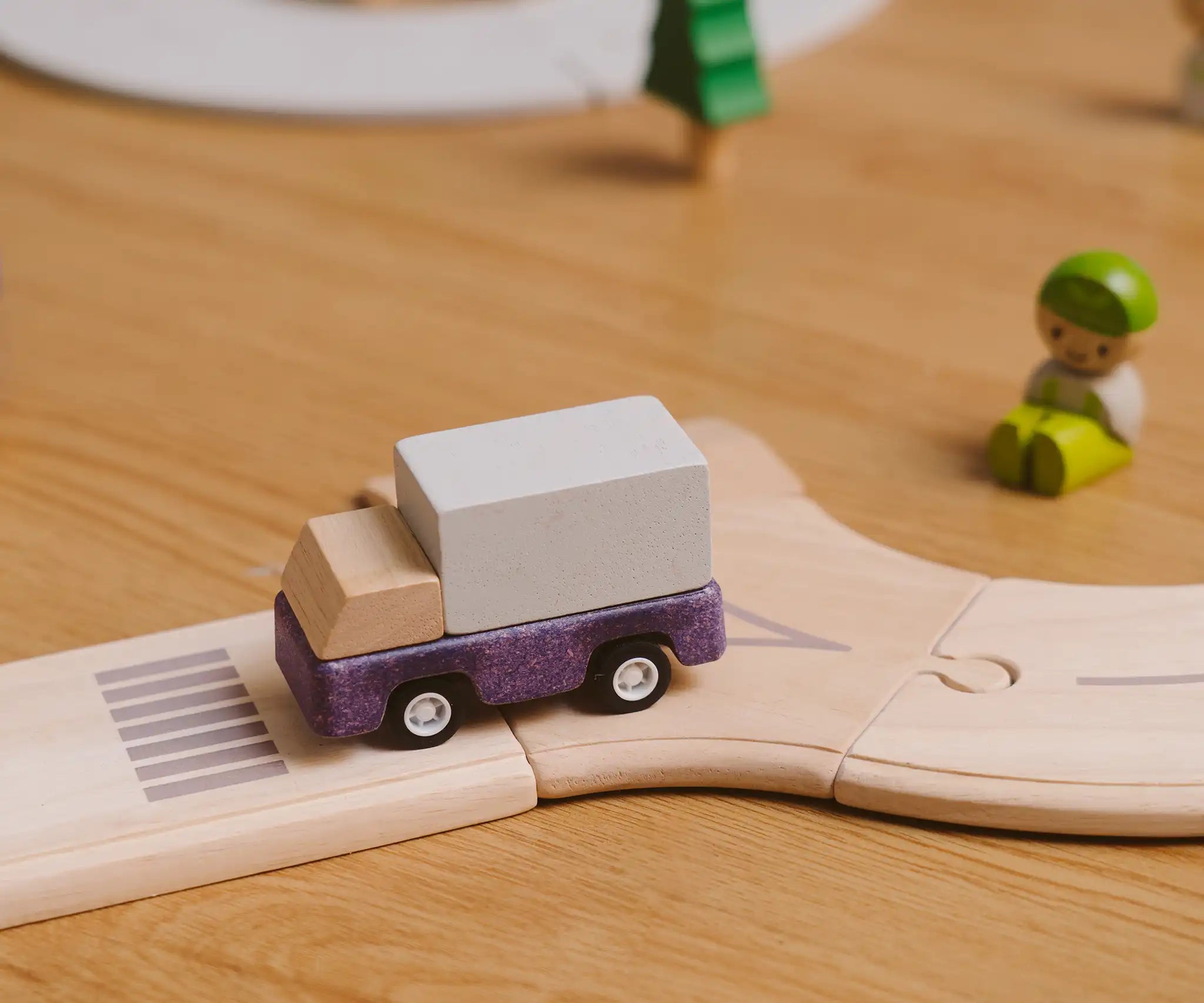 Purple truck from the PlanToys PlanWorld vehicle wooden toy vehicles set placed on a wooden PlanToys road.