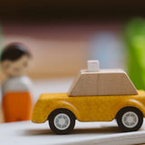 Yellow taxi car from the PlanToys PlanWorld vehicle wooden toy vehicles set placed on a rubber PlanToys road.