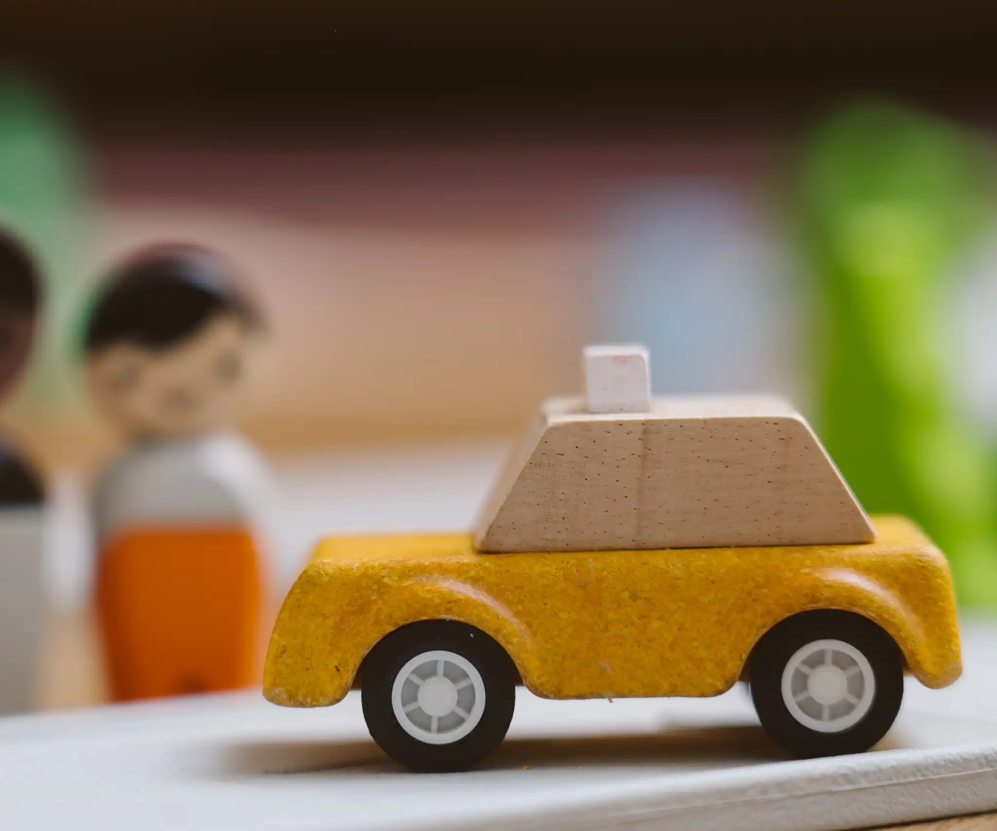 Yellow taxi car from the PlanToys PlanWorld vehicle wooden toy vehicles set placed on a rubber PlanToys road.