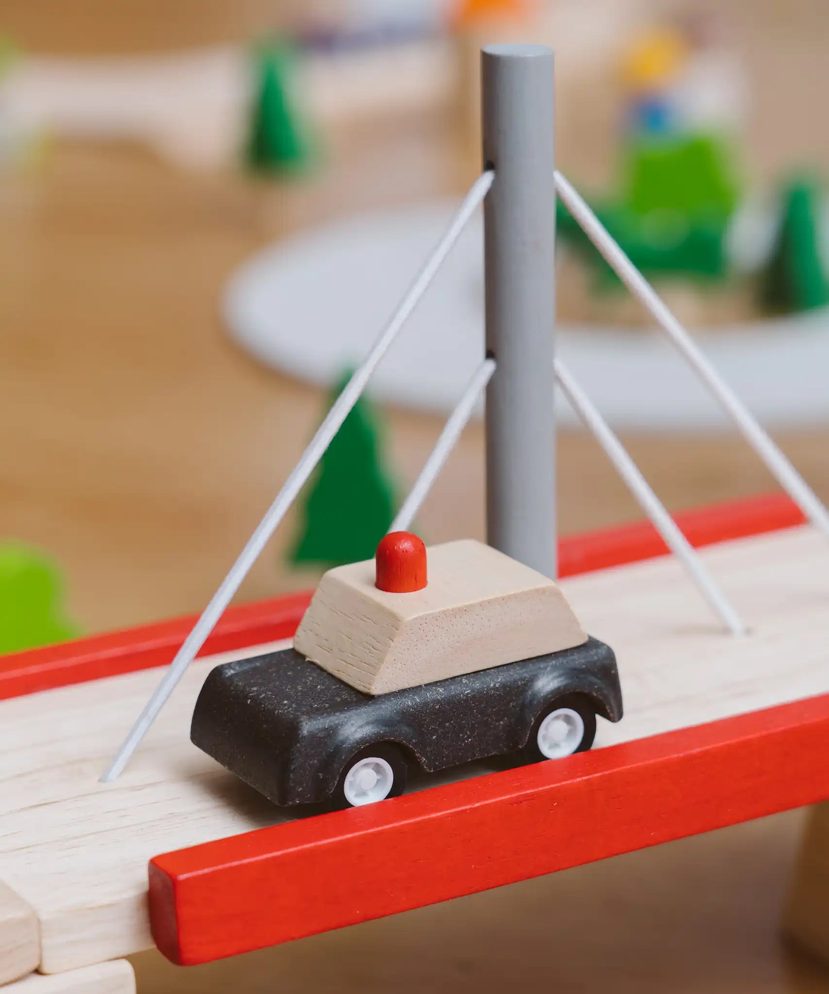 PlanToys wooden black taxi car toy vehicle on a PlanToys wooden bridge. 