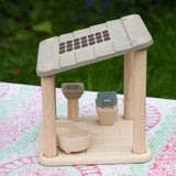 The PlanToys PlanSpace bathroom placed on a patterned tablecloth. The set can be used on it's own or with the other sets in the PlanSpace collection.